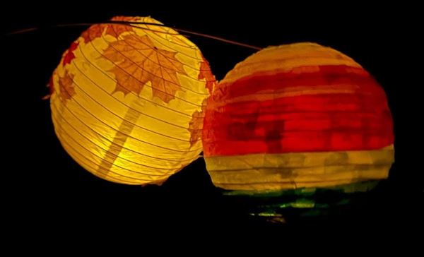 photo of 2 colourful paper lanterns glowing in the darkness.